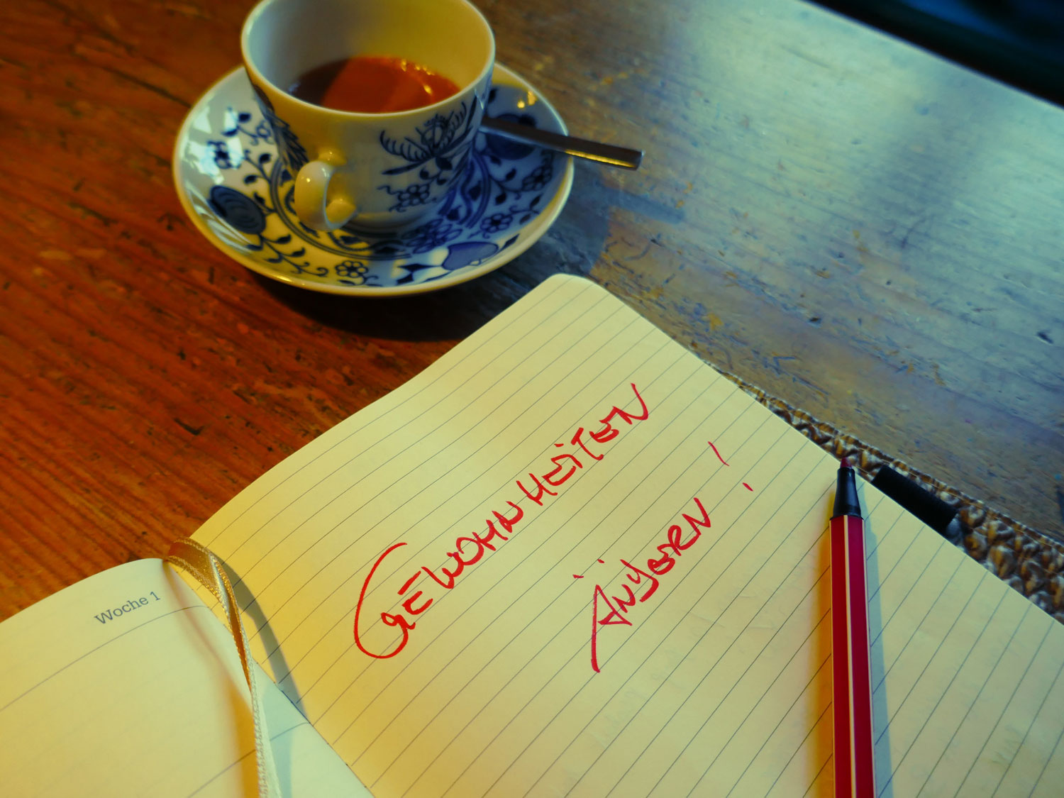 Eine Tasse Cafe oder Tee und davor ein Notizblock mit einer Beschriftung